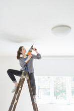 Woman As A Handyman With Drill On Ladder