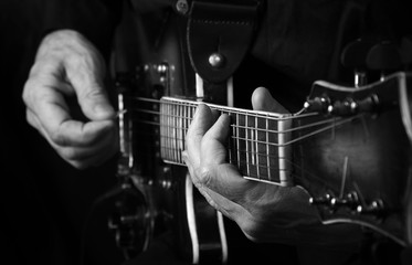 Wall Mural - Guitarist hands and guitar close up. playing electric guitar black and white.