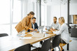 © rh2010 - Group of a young office employees dressed casually in the suits having some office work at the large meeting table in the bright office