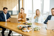 © rh2010 - Office workers sitting in the office with business lunches on the foreground. Concept of healthy takeaway food on the work