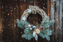 Christmas Wreath On Rustic Wooden Door Background Of Blue Tree.