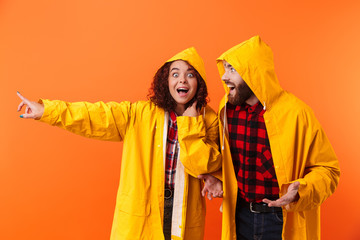 Canvas Print - Loving couple posing in yellow raincoats isolated