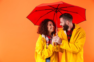 Canvas Print - Loving couple posing in yellow raincoats isolated