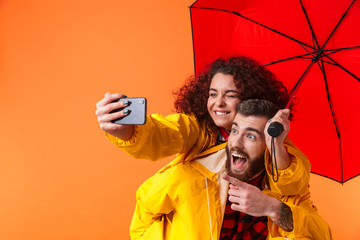 Poster - Loving couple posing in yellow raincoats isolated