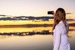 © Road Red Runner - Young girl at sunset taking a selfie with her smartphone, visiting the Albufera of Valencia, a nature reserve lake.