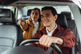 Fototapeta  - Smiling taxi driver with woman passenger pointing on road