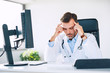 © baranq - Overworked doctor suffering from headache in work