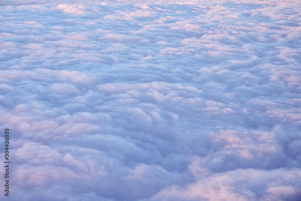 Beautiful clouds surface in sunset sky, view from plane during flight. Pink and blue cloudscape look like a snow. - obrazy, fototapety, plakaty 