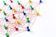 © Nana_studio - Network with colorful pins and string,  linked together with string on a white background suggesting a network of connections.