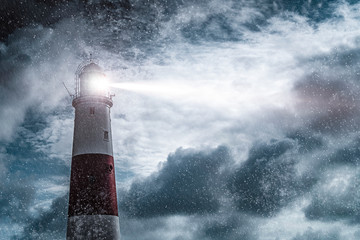 large lighthouse with bright search light on a dark and stormy night