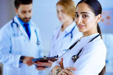 Attractive female arab doctor smiling in front of medical stuff in hospital