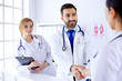 © khmelev - Young arab doctor shakes hands with a nurse in a hospital. Against the background of the human body