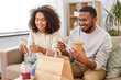 © Syda Productions - eating and people concept - happy african american couple with takeaway food and drinks at home