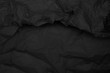 Black crumpled paper texture, dark background