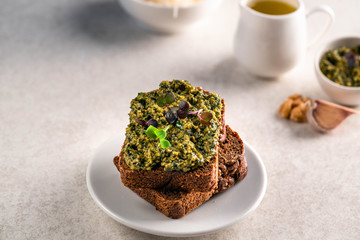 healthy breakfast (snack) of rye bread and mashed avocado on a light plate, olive oil and garlic cloves on the background