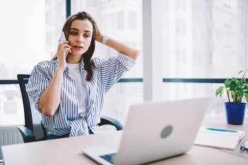 Wall Mural - pensive young woman calling to operator of customer support update software on laptop computer in of