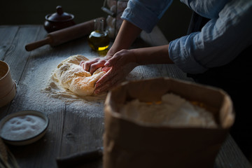 Hands knead the dough for pizza making. Fresh raw dough for pizza or bread baking on wooden board.