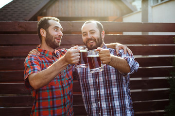 Two happy friends with beer glasses in the hands of nature.