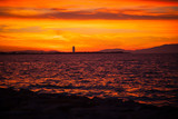 Fototapeta  - A full sun setting over the sea, reflecting in the water