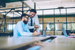 © BullRun - Professional men discussing ideas of productive strategy for company during searching information on content website via modern netbook, male experts downloading media file for creating new website