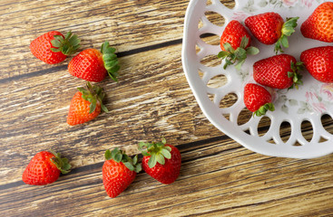 Strawberries on a decorated plate and over a wooden table