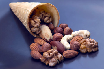 Different types of nuts in a waffle cone on a gray background. Healthy and protein food