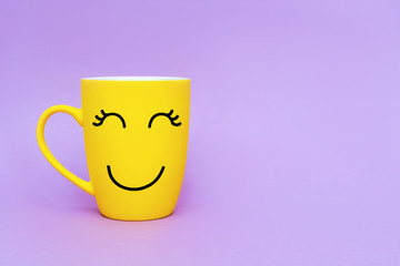 Wall Mural - Smiley yellow coffee cup on purple background. Happy friday word concept. Minimalism style, romantic mood, good morning, happiness, break time