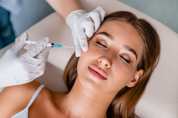young woman gets beauty facial injections in salon