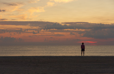 dawn at beach woman pondering the surf and pastel colored sky