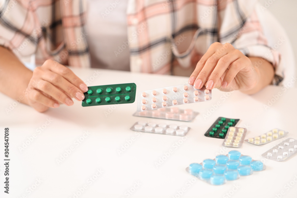 Young woman with different pills at home, closeup