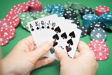 Wall Mural - Royal Flush cards in female hands and poker chips on green flat lay background.