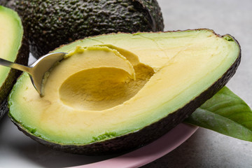 Eating of fresh ripe green organic hass avocado fruit with spoon