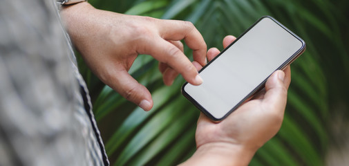 Cropped shot of professional businessman using mock up smartphone with garden background