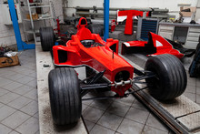 The Process Of Repairing And Restoring A Red Sports Car At A Pitstop In The Service Station Or A Repair Workshop On A Lift.