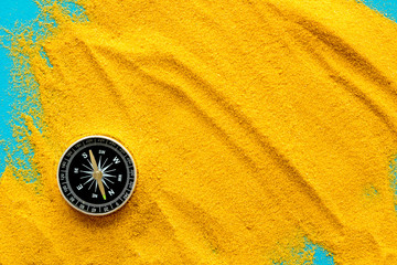 Wall Mural - Travel concept. Compass on yellow sand background top view copy space