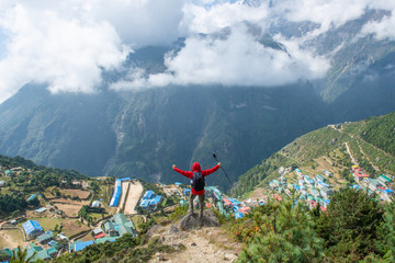 Wall Mural - Tourist standing on the mountains edge and looking below to scenery view of Namche Bazaar the largest village in Khumbu region in Nepal.