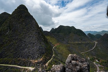 Sticker - High angle shot of high green mountains with curvy roads under the cloudy sky