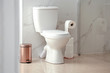 Modern toilet bowl with roll of paper in bathroom