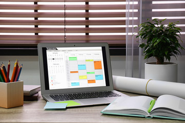 Poster - Laptop with calendar on wooden table in office