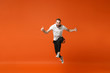 © ViDi Studio - Crazy young man in casual white t-shirt posing isolated on orange wall background studio portrait. People lifestyle concept. Mock up copy space. Having fun, fooling around, jumping, showing thumbs up.