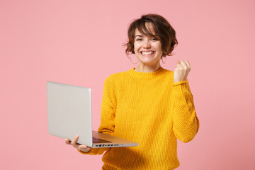 smiling young brunette woman girl in yellow sweater posing isolated on pink wall background studio p