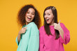 © ViDi Studio - Two women friends european african american girls in pink green clothes, crowns posing isolated on yellow background. People lifestyle concept. Mock up copy space. Point index finger showing thumb up.