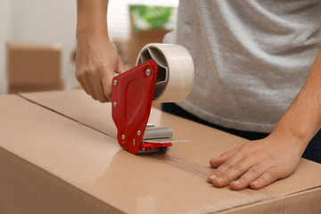 Woman packing cardboard box indoors, closeup. Moving day