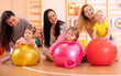 © Oksana Kuzmina - Group of mothers and their kids doing yoga exercises on gymnastic balls at fitness gym