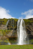 Fototapeta Tęcza - Seljalandsfoss Waterfall in Iceland. A famous waterfall with a path to walk behind the falls.