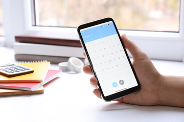 Canvas Print - Woman using calendar app on smartphone indoors, closeup