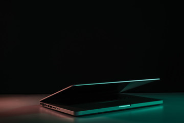 Aufkleber - Beautiful silver laptop in the color light on a table and night background.