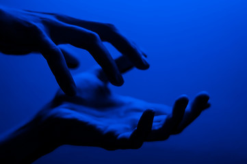 Hands in monochrome blue contrast neon light. Man showing hand palm gesture sign. Artistic photography.