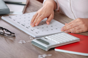 Canvas Print - Woman with calendar at wooden table, closeup