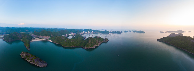 Wall Mural - Aerial unique view Vietnam Cat Ba bay with floating fishing boats on sea, cloudscape tropical weather inspirational sunset, epic city skyline and skyscraper, scenic green mountain.